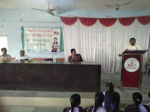a white kitten with brown and black spots sitting with its paws slightly outstretched.