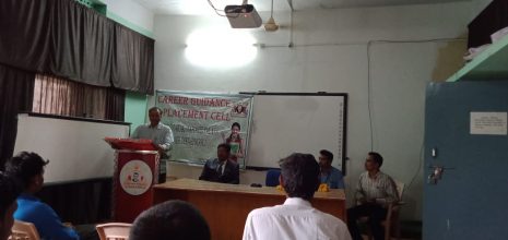 a white kitten with brown and black spots sitting with its paws slightly outstretched.